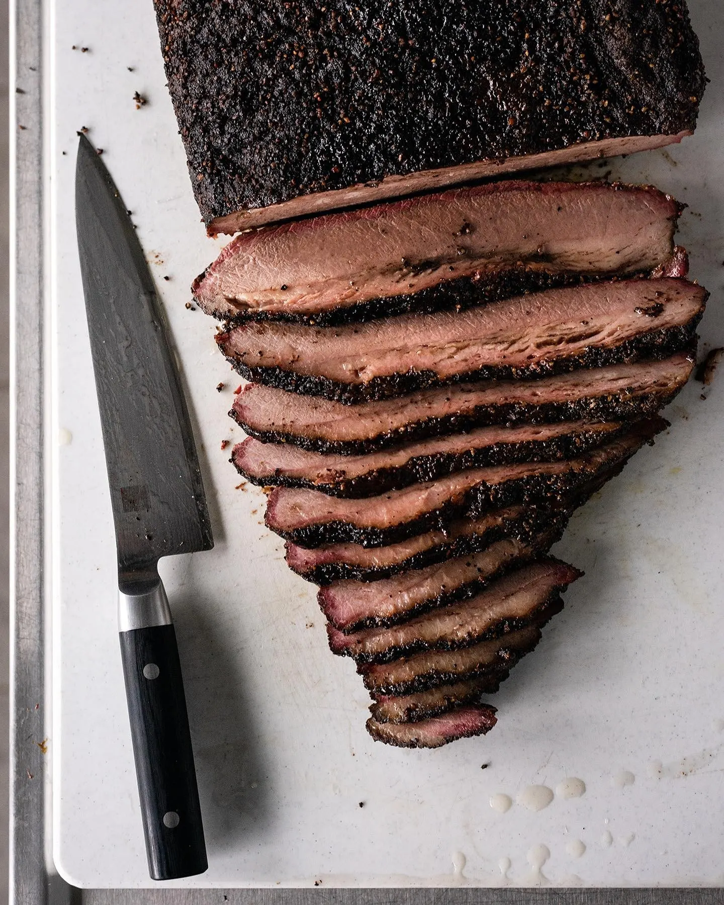 Sliced 14-hour oak smoked brisket with a chef's knife